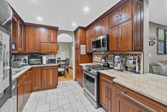 9 Schnabl Ct, Wappingers Falls, NY 12590 - kitchen with appliances with stainless steel finishes, backsplash, light stone countertops, recessed lighting, and arched walkways