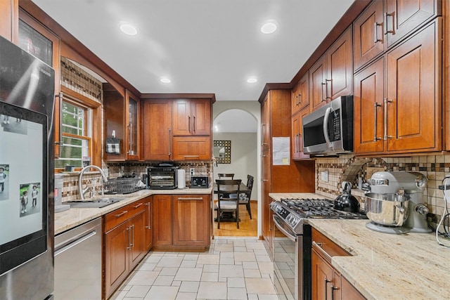9 Schnabl Ct, Wappingers Falls, NY 12590 - kitchen with stainless steel appliances, arched walkways, light stone countertops, decorative backsplash, and glass insert cabinets