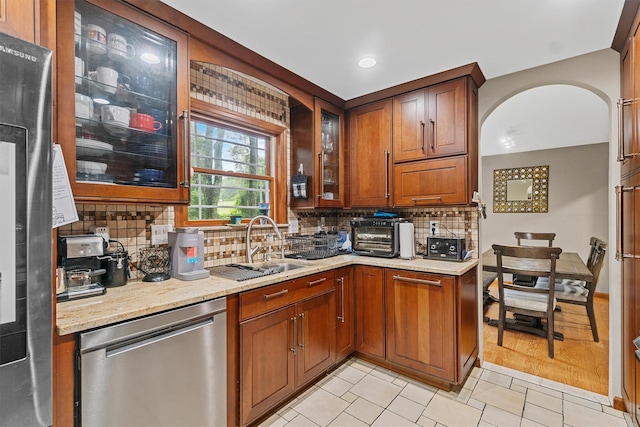 9 Schnabl Ct, Wappingers Falls, NY 12590 - kitchen with stainless steel dishwasher, tasteful backsplash, light stone counters, glass insert cabinets, and light tile patterned flooring