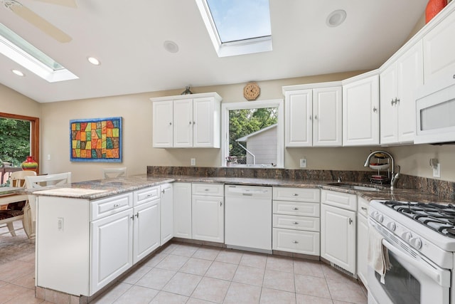 41 Whitman St, Congers, NY 10920 - kitchen with white appliances, a skylight, lofted ceiling, white cabinetry, and a peninsula