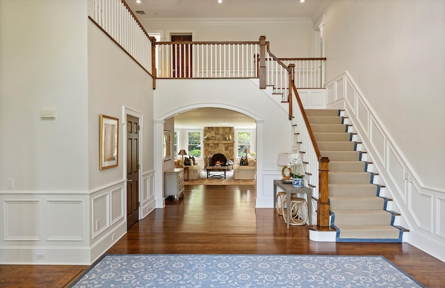 1 Simon Ct, Quogue, NY 11959 - foyer entrance with a decorative wall, stairs, a stone fireplace, wood finished floors, and arched walkways