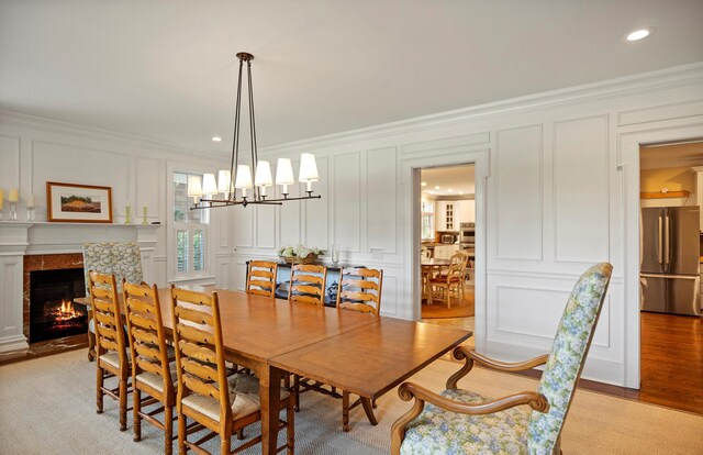 1 Simon Ct, Quogue, NY 11959 - dining room with a decorative wall, crown molding, a chandelier, a tile fireplace, and light wood-style floors