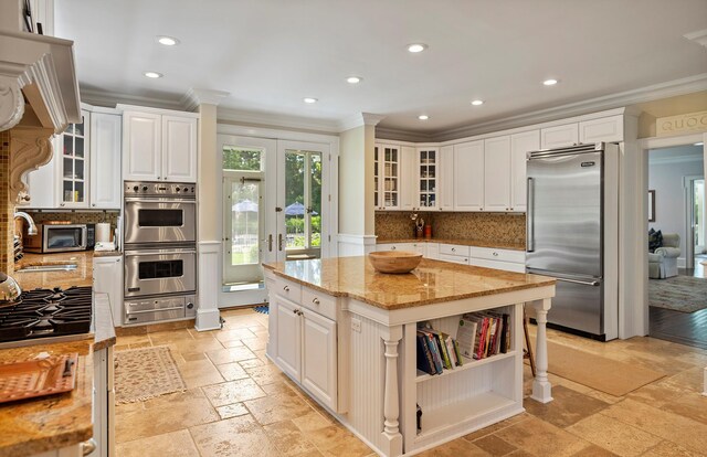 1 Simon Ct, Quogue, NY 11959 - kitchen with appliances with stainless steel finishes, crown molding, a warming drawer, light stone counters, and stone tile floors