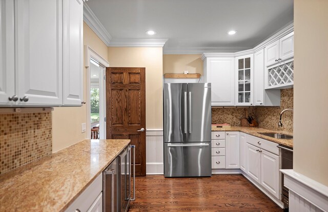 1 Simon Ct, Quogue, NY 11959 - kitchen featuring appliances with stainless steel finishes, glass insert cabinets, white cabinets, light stone counters, and ornamental molding