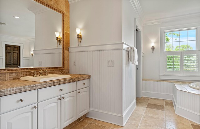 1 Simon Ct, Quogue, NY 11959 - bathroom with ornamental molding, vanity, a wainscoted wall, a tub to relax in, and stone tile floors