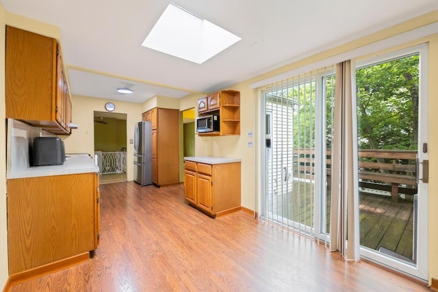 1291 Minerva Ave, West Islip, NY 11795 - kitchen with appliances with stainless steel finishes, open shelves, light countertops, a skylight, and light wood finished floors