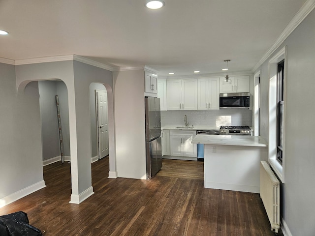 300 Richbell Rd Unit B2, Mamaroneck, NY 10543 - kitchen with stainless steel appliances, radiator, arched walkways, tasteful backsplash, and white cabinetry