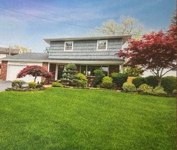 404 Club Ct, Oceanside, NY 11572 - traditional-style home featuring an attached garage, a front lawn, and driveway