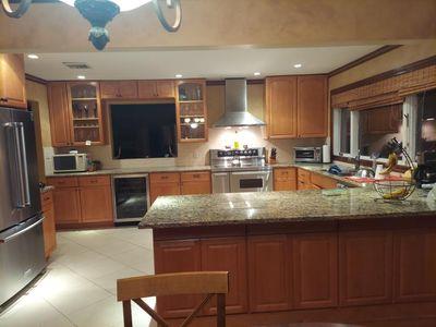 404 Club Ct, Oceanside, NY 11572 - kitchen with wall chimney exhaust hood, beverage cooler, appliances with stainless steel finishes, glass insert cabinets, and brown cabinets