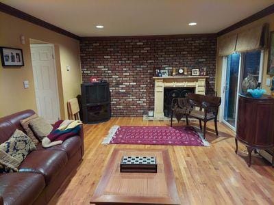 404 Club Ct, Oceanside, NY 11572 - living area featuring wood finished floors, ornamental molding, brick wall, and a fireplace
