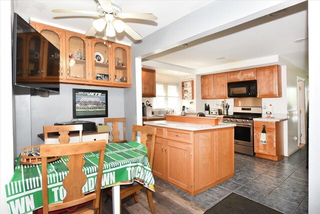 218 Mott St, Oceanside, NY 11572 - kitchen with black microwave, stainless steel gas stove, light countertops, glass insert cabinets, and a ceiling fan