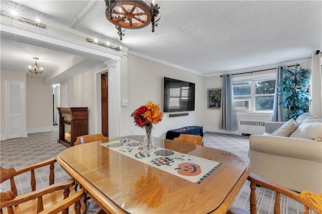 51 White Oak St Unit 2A, New Rochelle, NY 10801 - carpeted dining area featuring radiator heating unit, a chandelier, a textured ceiling, and a glass covered fireplace