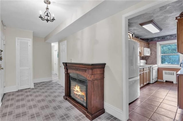 51 White Oak St Unit 2A, New Rochelle, NY 10801 - kitchen featuring white appliances, radiator, a glass covered fireplace, a chandelier, and light countertops