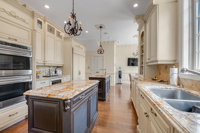 760 Hillcrest Pl, North Woodmere, NY 11581 - kitchen featuring double oven, cream cabinets, a center island with sink, a chandelier, and recessed lighting
