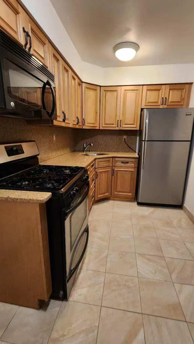 222 Capstan Ct Unit 101B, College Point, NY 11356 - kitchen with stainless steel appliances, tasteful backsplash, light tile patterned flooring, brown cabinets, and light stone countertops