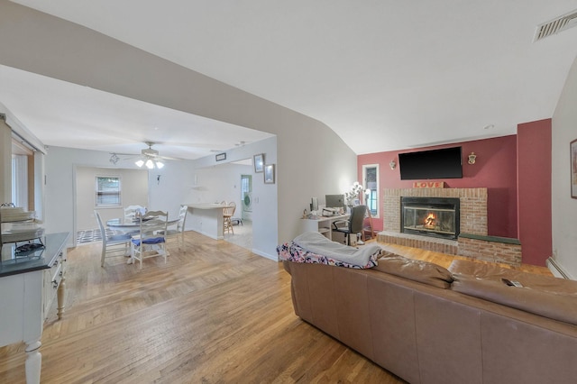 8 Peconic Ln, Selden, NY 11784 - living room with a fireplace, a baseboard radiator, light wood finished floors, a ceiling fan, and lofted ceiling