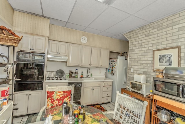 2541 83rd St, East Elmhurst, NY 11370 - kitchen featuring black appliances, a warming drawer, a drop ceiling, under cabinet range hood, and light tile patterned flooring