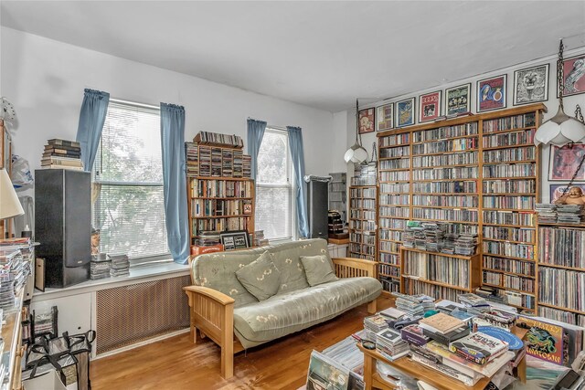2541 83rd St, East Elmhurst, NY 11370 - living area with radiator heating unit, wood finished floors, and wall of books