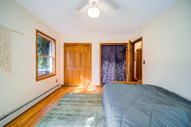 322 Union School Rd, Middletown, NY 10941 - bedroom featuring a baseboard heating unit, light wood-style flooring, ceiling fan, and two closets