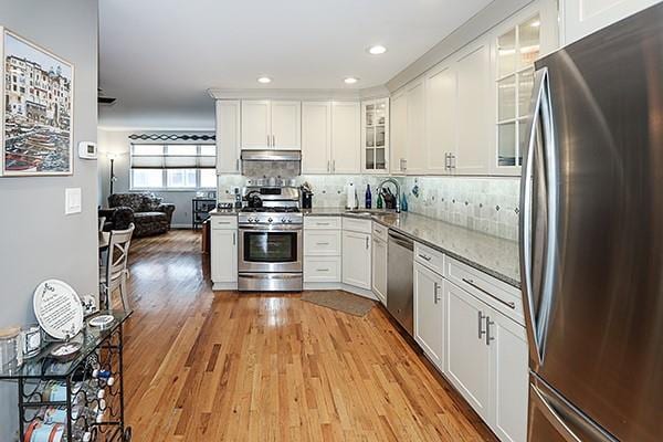 183 Atlantic Ave Unit 8, Lynbrook, NY 11563 - kitchen with stainless steel appliances, under cabinet range hood, tasteful backsplash, white cabinetry, and recessed lighting