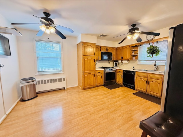 945 Swinton Ave, Bronx, NY 10465 - kitchen with black appliances, radiator heating unit, ceiling fan, and plenty of natural light