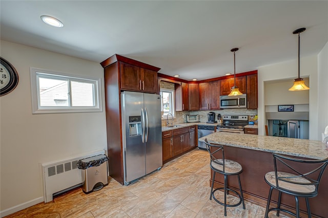 17 Abbott St, West Babylon, NY 11704 - kitchen with appliances with stainless steel finishes, radiator heating unit, light stone countertops, a kitchen breakfast bar, and tasteful backsplash