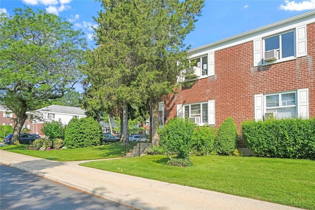 22401 Hillside Ave Unit 2, Queens Village, NY 11427 - view of front facade with brick siding, a front lawn, and cooling unit