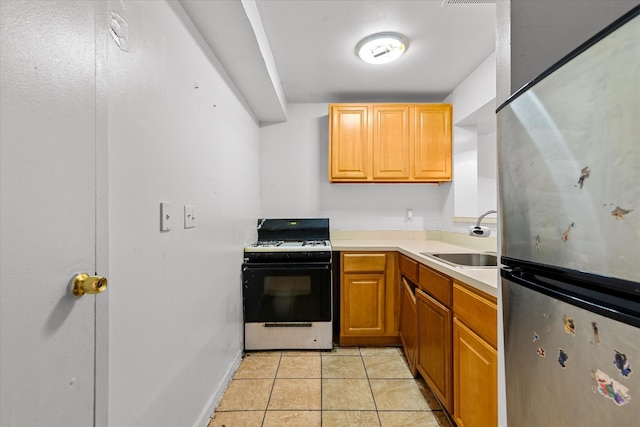 718 Garden St, Bronx, NY 10457 - kitchen with gas range, freestanding refrigerator, light countertops, and light tile patterned floors