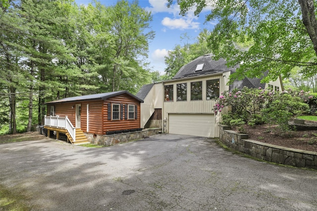 295 N Salem Rd, Waccabuc, NY 10597 - view of front of house featuring asphalt driveway, a garage, a shingled roof, faux log siding, and a wooden deck