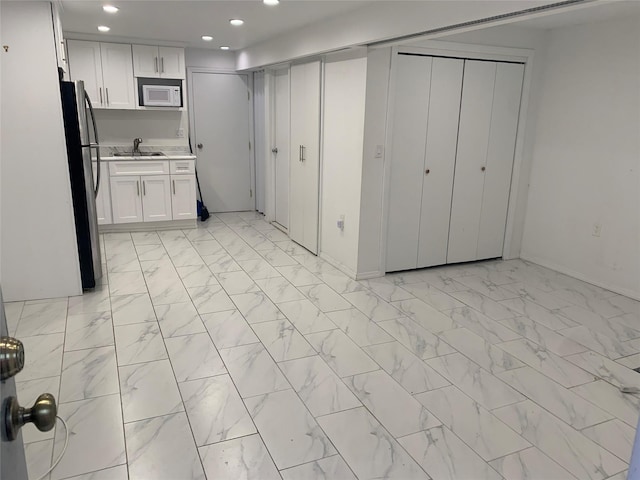 1004 Rhinelander Ave, Bronx, NY 10462 - kitchen featuring white microwave, freestanding refrigerator, recessed lighting, white cabinets, and light marble finish flooring