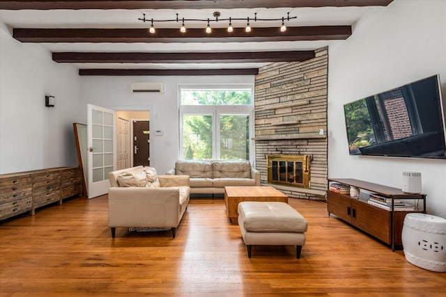 88-37 74th Ave, Glendale, NY 11385 - living area featuring a wall unit AC, wood finished floors, a fireplace, beam ceiling, and french doors