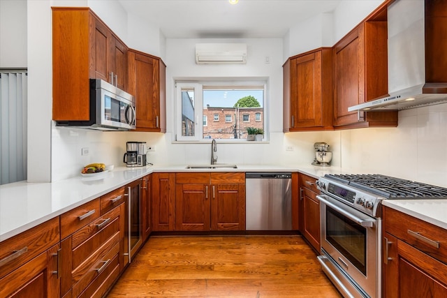 88-37 74th Ave, Glendale, NY 11385 - kitchen featuring appliances with stainless steel finishes, wall chimney exhaust hood, a wall unit AC, wood finished floors, and light countertops