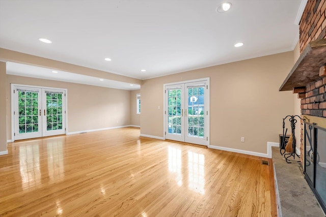 51 Highfield Ave, Port Washington, NY 11050 - unfurnished living room featuring a brick fireplace, french doors, light wood-style floors, and recessed lighting