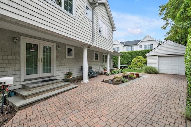 51 Highfield Ave, Port Washington, NY 11050 - view of patio featuring french doors, an outdoor structure, a garage, and decorative driveway