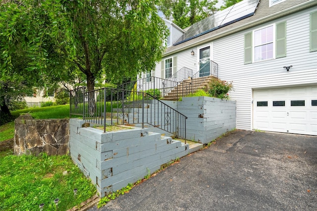 18 Jenkins Ct, Ossining, NY 10562 - view of front facade with a garage, asphalt driveway, and solar panels