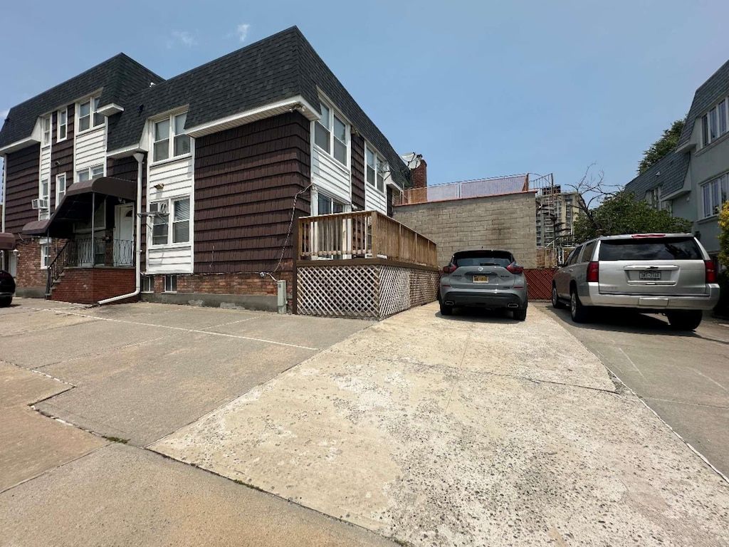 214-04 18th Ave, Bayside, NY 11360 - view of side of property with roof with shingles, mansard roof, and concrete driveway