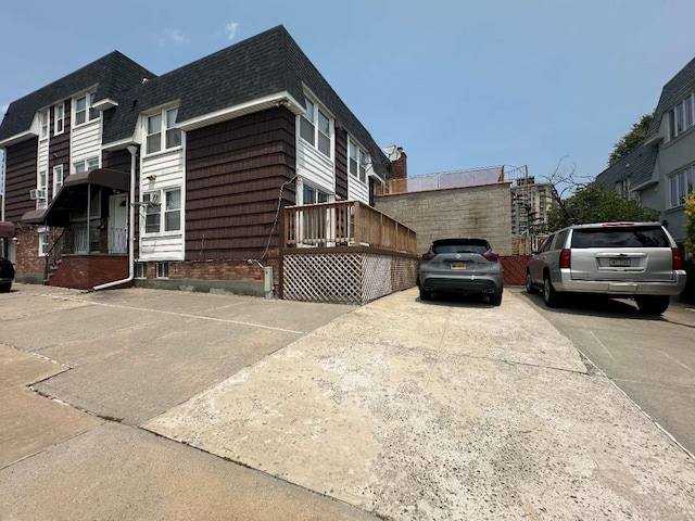 214-04 18th Ave, Bayside, NY 11360 - view of side of property with roof with shingles, mansard roof, and concrete driveway