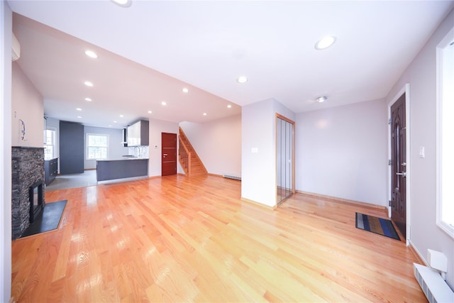 1768 W 5th St, Brooklyn, NY 11223 - unfurnished living room with stairway, recessed lighting, light wood-style flooring, a stone fireplace, and a baseboard radiator