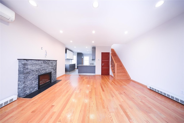1768 W 5th St, Brooklyn, NY 11223 - unfurnished living room featuring an AC wall unit, a fireplace, recessed lighting, stairway, and light wood-style flooring