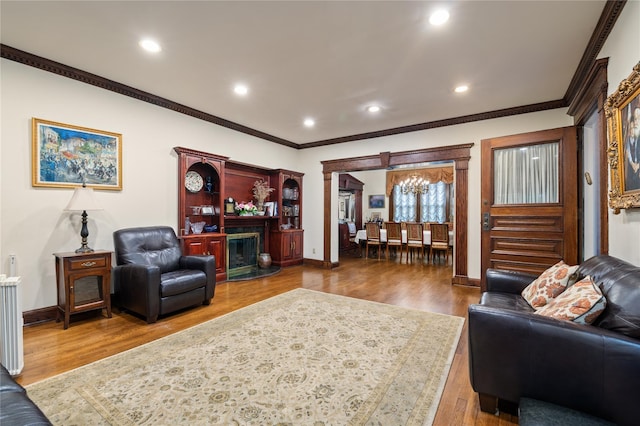 1020 New Mcneil Ave, Lawrence, NY 11559 - living area with a chandelier, ornamental molding, wood finished floors, recessed lighting, and a glass covered fireplace