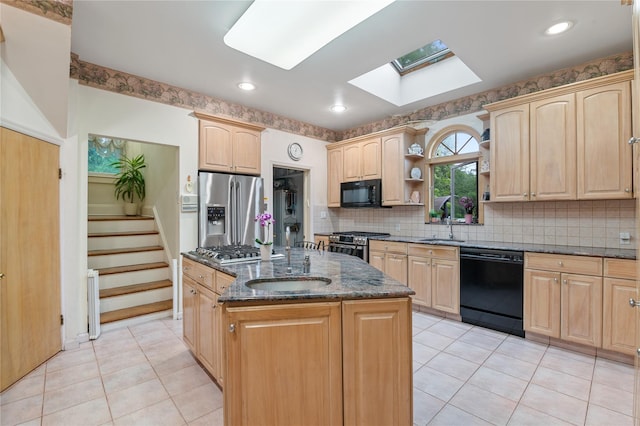 1020 New Mcneil Ave, Lawrence, NY 11559 - kitchen featuring black appliances, a skylight, light brown cabinets, dark stone countertops, and a center island