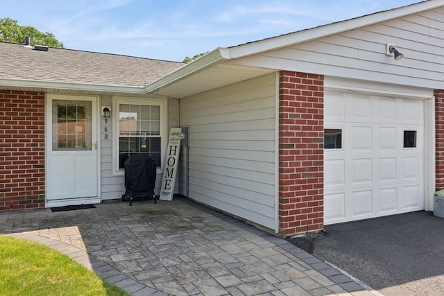 96 Enfield Ct Unit B, Ridge, NY 11961 - view of exterior entry with a garage, brick siding, and roof with shingles