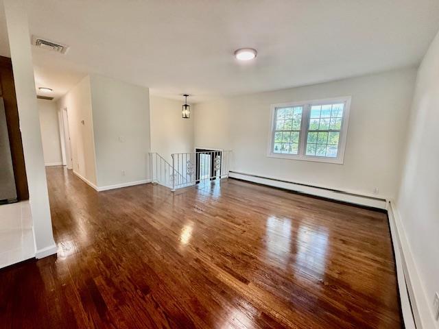 30 7th St, Holbrook, NY 11741 - empty room with wood finished floors, a baseboard radiator, and baseboard heating