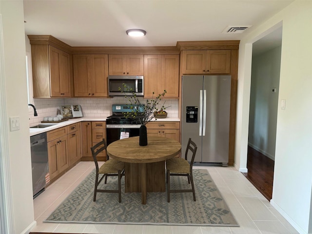 30 7th St, Holbrook, NY 11741 - kitchen with appliances with stainless steel finishes, backsplash, light countertops, and light tile patterned floors