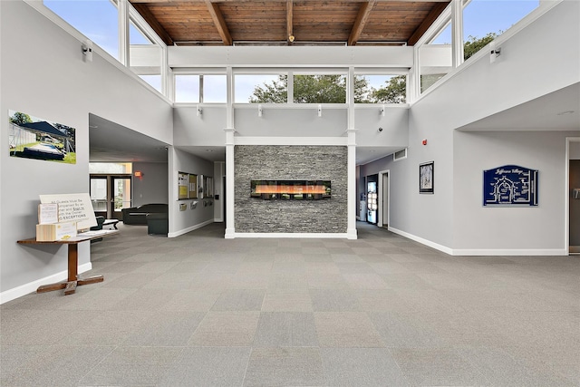 84 Molly Pitcher Ln Unit H, Yorktown Heights, NY 10598 - unfurnished living room featuring a wood ceiling with exposed beams, a high ceiling, carpet floors, and a stone fireplace