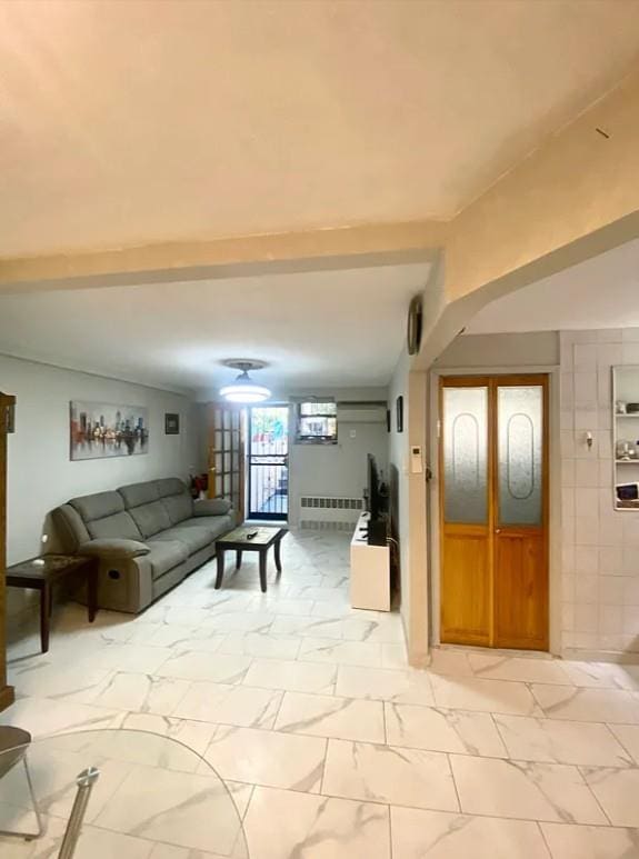22-39 74th St, East Elmhurst, NY 11370 - living room with radiator heating unit, beamed ceiling, and light marble finish floors