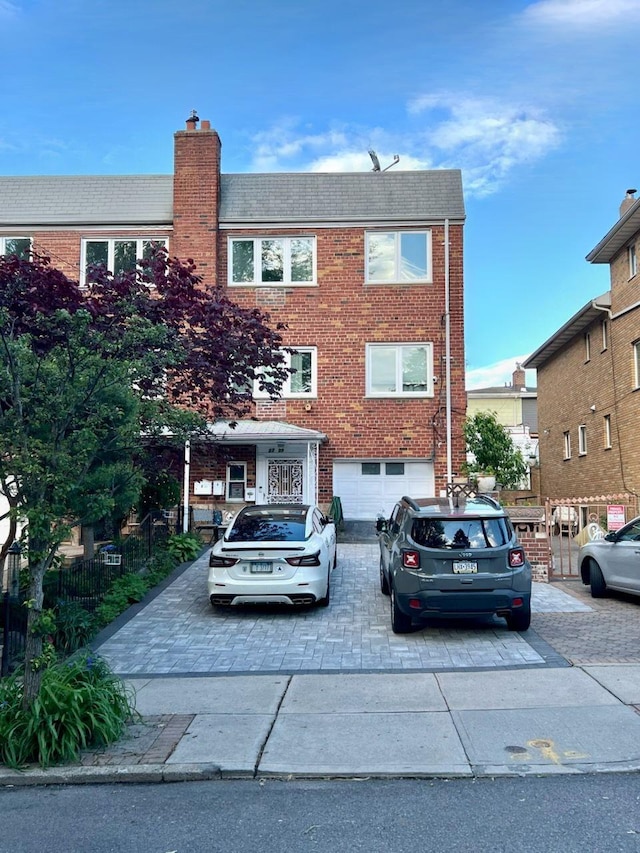 22-39 74th St, East Elmhurst, NY 11370 - view of front of home with driveway, brick siding, an attached garage, a chimney, and roof with shingles