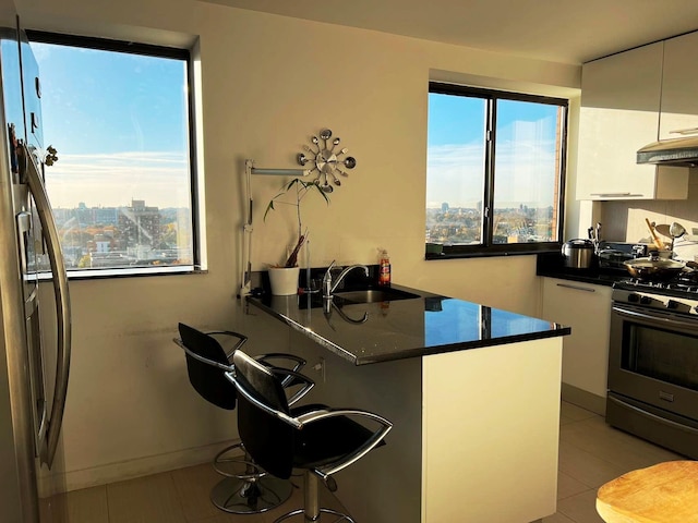 132-35 41st Rd Unit 14B, Flushing, NY 11355 - kitchen with gas stove, dark countertops, white cabinetry, a kitchen breakfast bar, and a peninsula