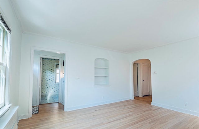 147 Nugent St, New Hyde Park, NY 11040 - spare room with arched walkways, light wood finished floors, crown molding, healthy amount of natural light, and built in shelves