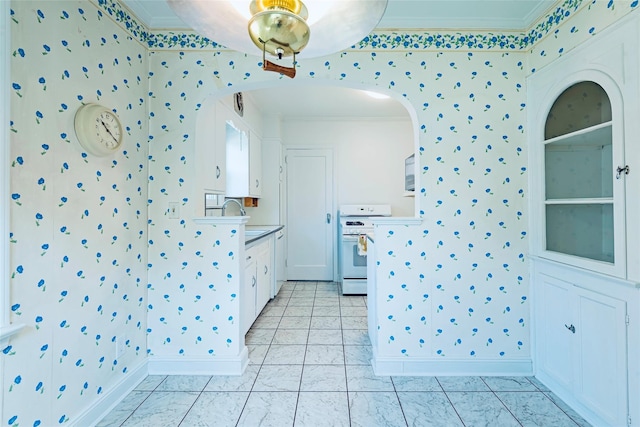 147 Nugent St, New Hyde Park, NY 11040 - kitchen featuring wallpapered walls, white range with gas cooktop, ornamental molding, white cabinetry, and arched walkways